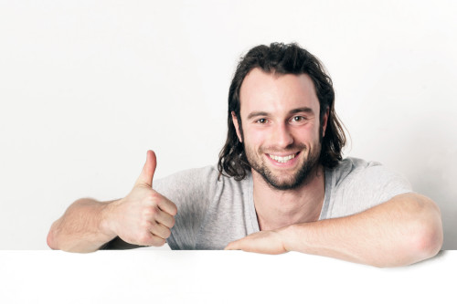 Junger Mann vor weißem Hintergrund Junger Mann mit Daumen nach oben