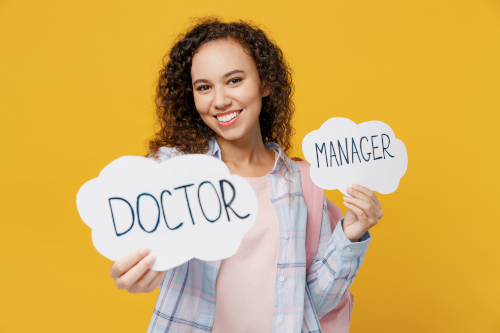 Arzt und Unternehmer Junge lächelnde Frau hält zwei Wortwolken "Doctor" und "Manager" in den Händen